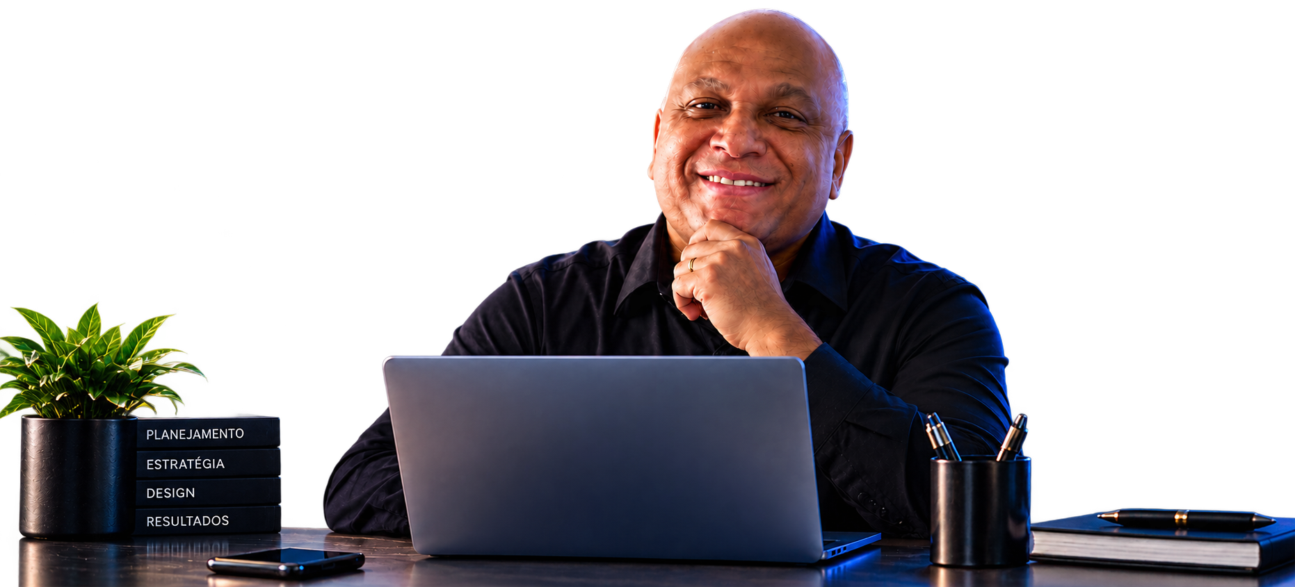 Agnaldo Barreto sorrindo em sua mesa com notebook